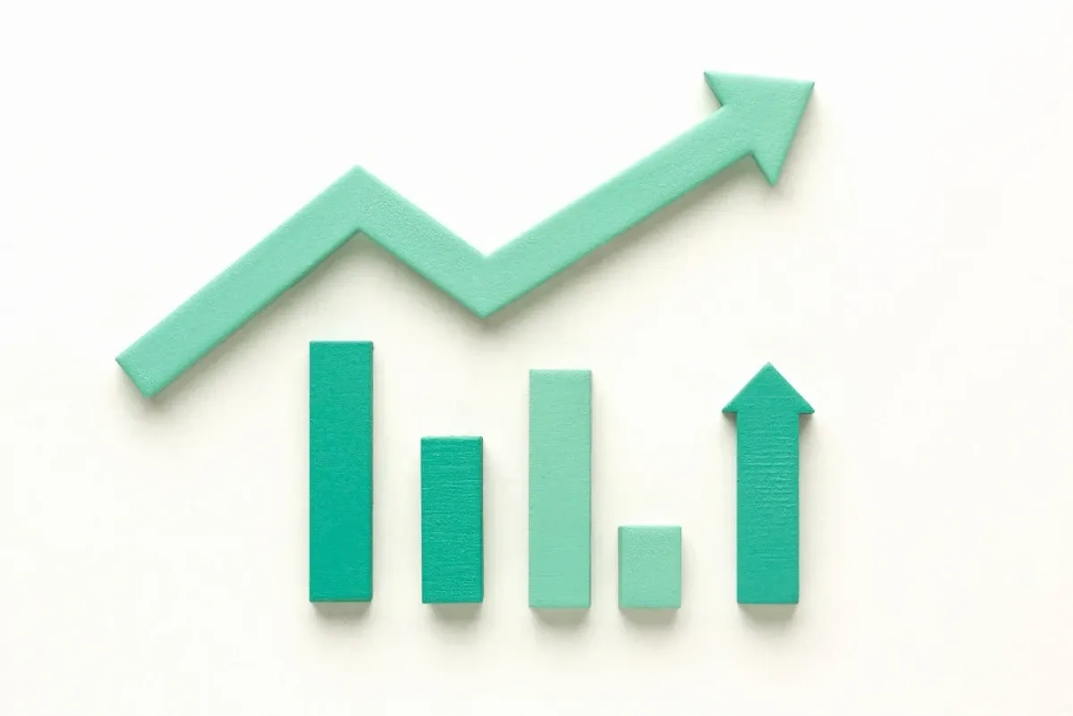 Green paper bar chart with an upward zigzag arrow on a white background