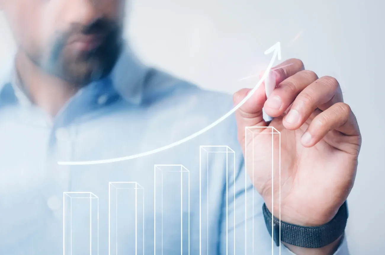 A man draws a rising arrow over a bar chart on a transparent screen